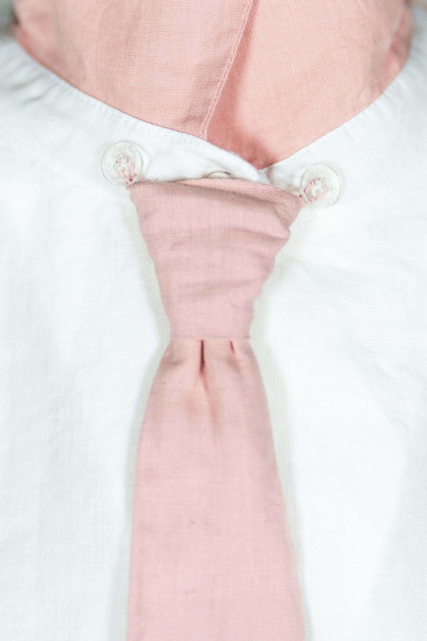 Close-up of a Linen Blouse featuring a pink attachable tie and button details.