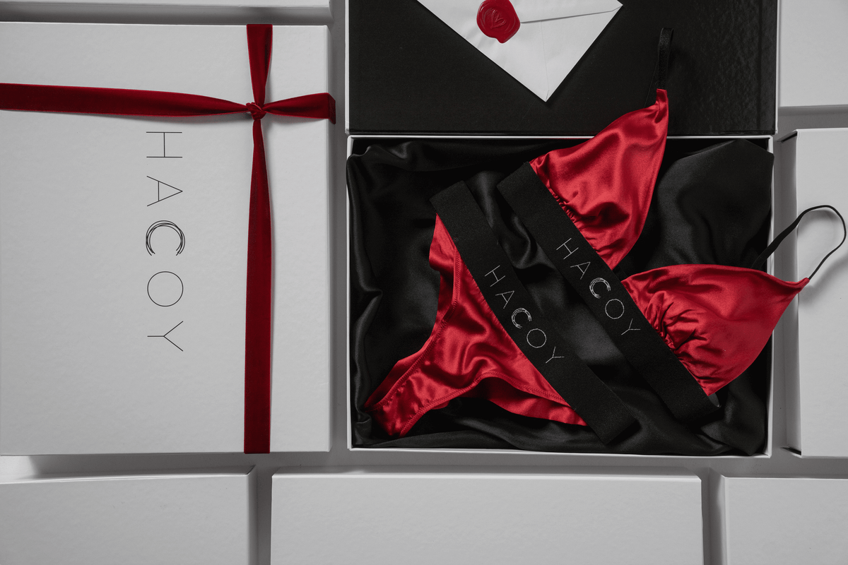 Elegant red satin lingerie set displayed in a luxurious HACOY gift box with an envelope and ribbon.