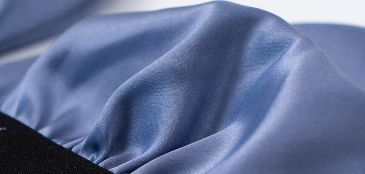 Close-up of luxurious blue satin fabric showcasing its smooth texture, ideal for high-end garments.