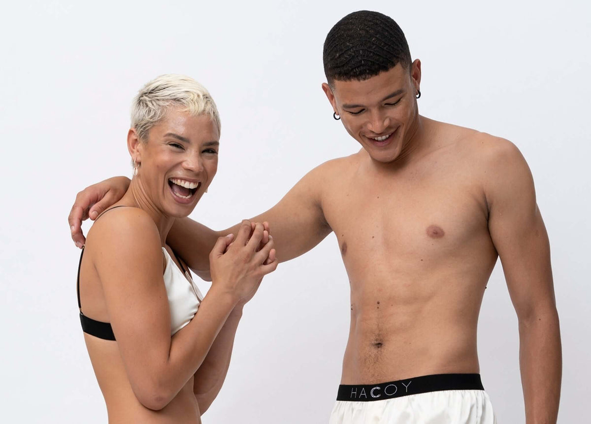 Two models showcasing HACOY's fashion line, smiling and enjoying a playful moment in stylish apparel.