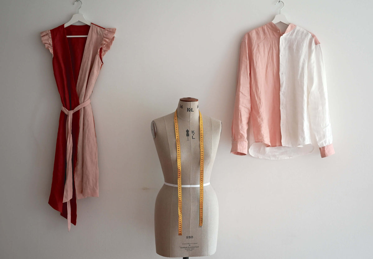 Fashion design studio with a dress and shirt on mannequins, showcasing tailored garments and measuring tape.